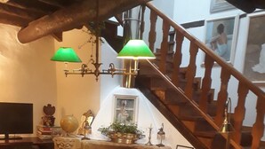 A cozy living room with a fireplace, books, and a staircase. - A Cortiña de Canalarrana (Ribadeo)