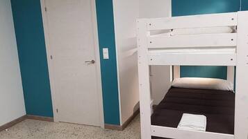 A bunk bed with a white frame and a brown mattress, a white door, and teal walls.