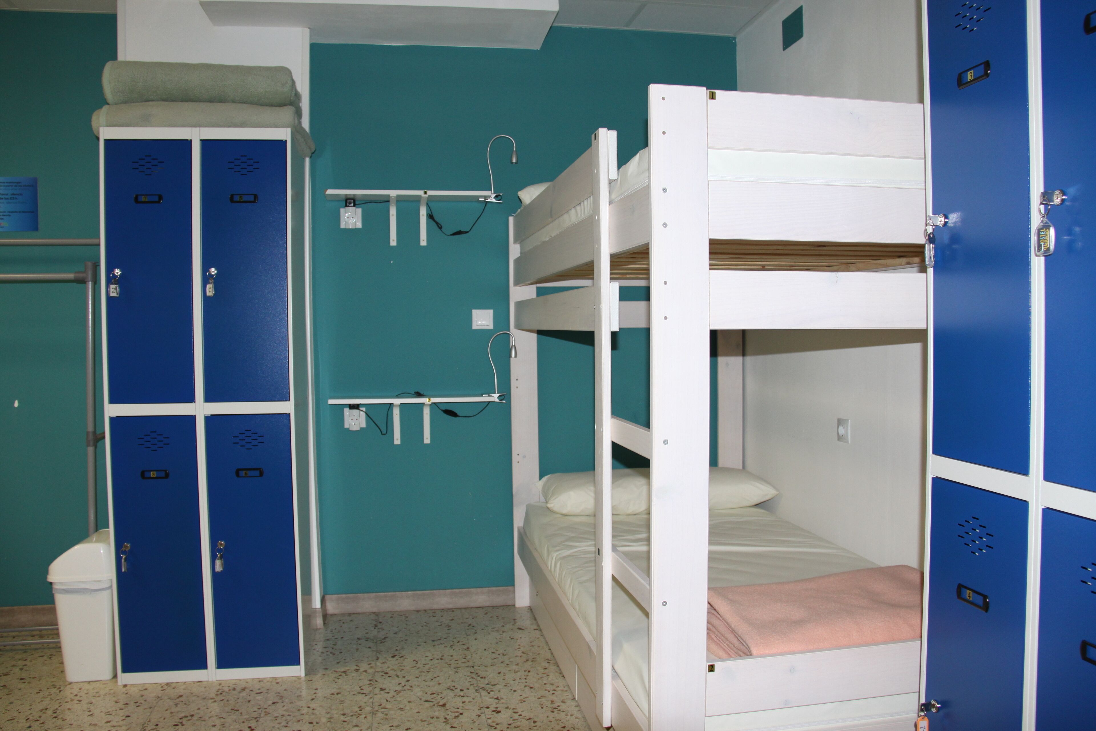 Une chambre avec un lit superposé, un placard bleu et un placard blanc.