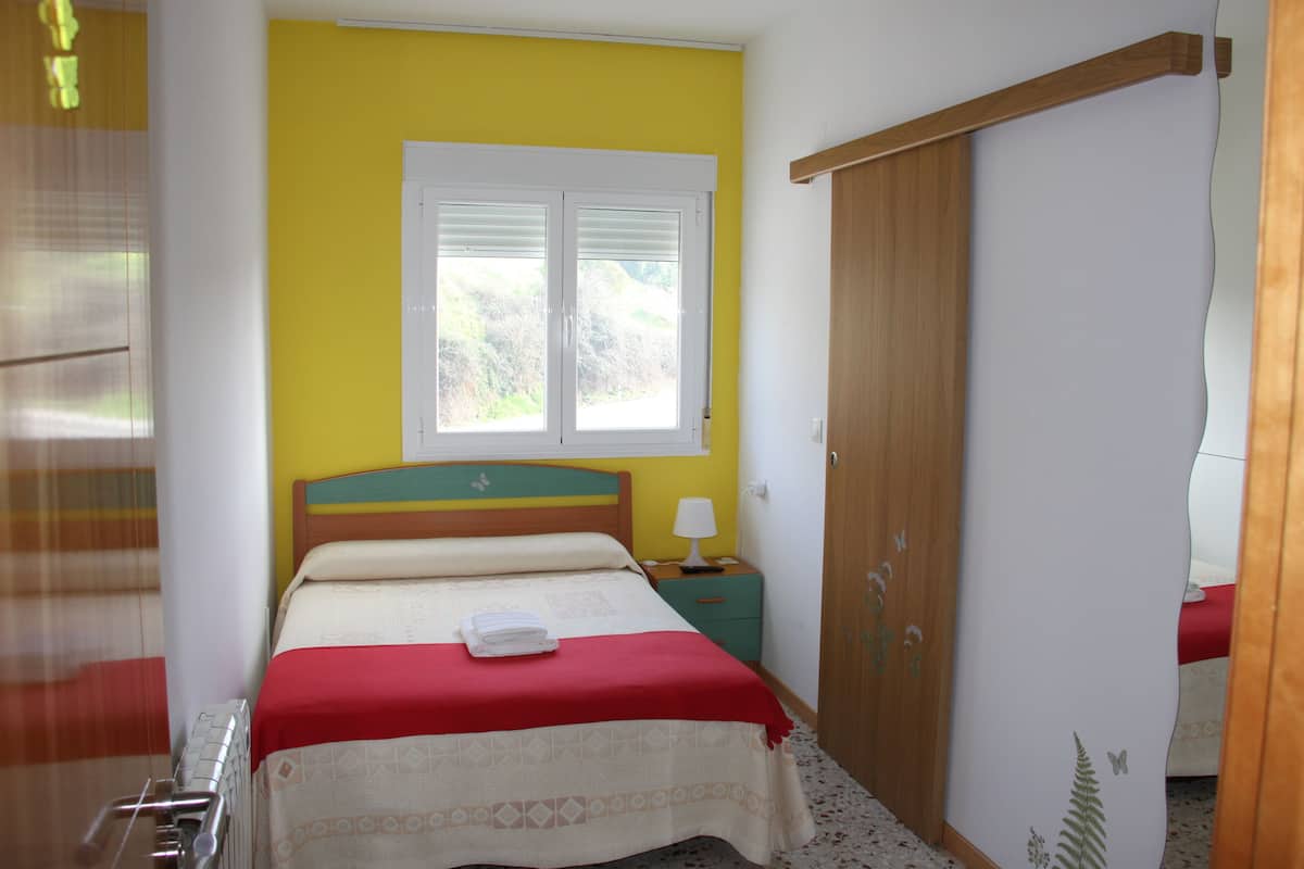Une chambre à coucher avec un lit, une table de chevet, une fenêtre et une armoire.