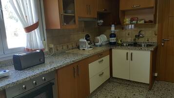 Una cocina con armarios de madera, encimera de granito, tostadora, hervidor y pileta.