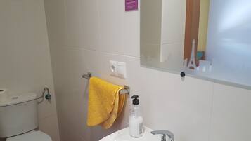 A bathroom with a white toilet, a sink with a chrome faucet, and a yellow towel hanging on a rack.