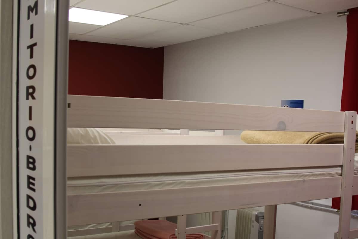 Une chambre de dortoir avec des lits superposés, un plafond blanc et un mur rouge.