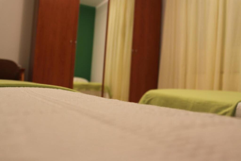 Ett hotellrum med en säng, en grön stol och en spegel.