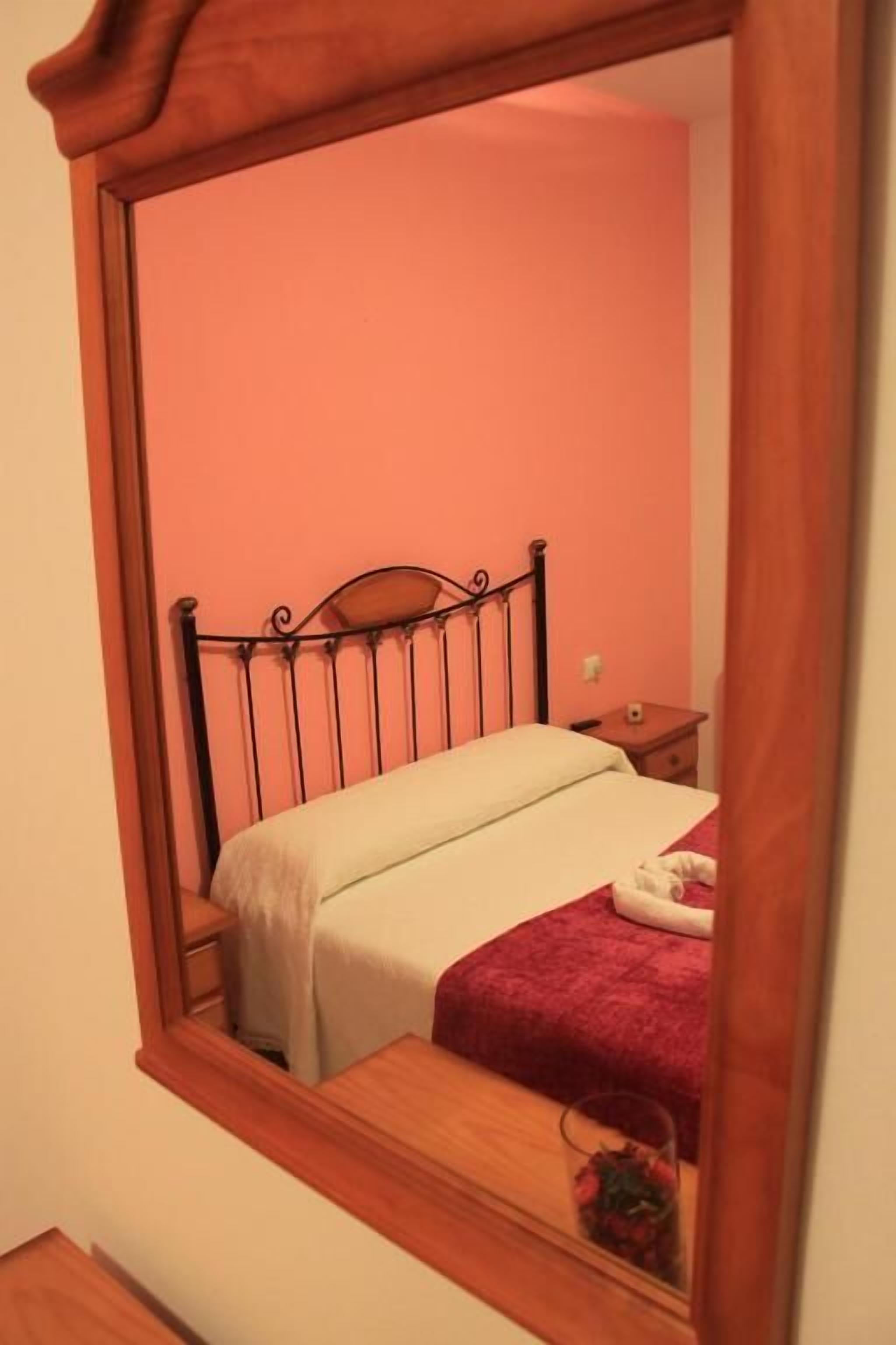 A bedroom with a bed, a nightstand, and a mirror.