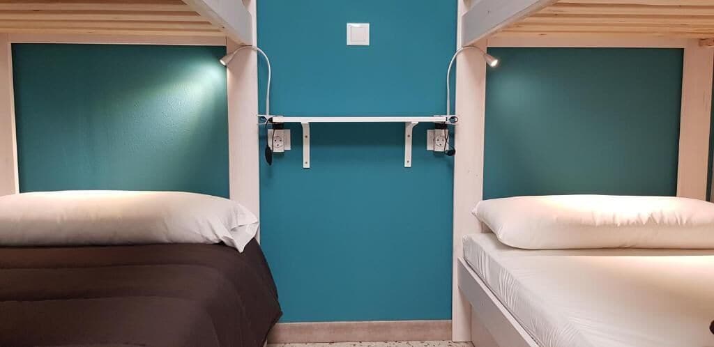 Una habitación con dos camas, paredes verde azulado y techo blanco.