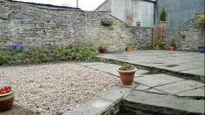 A stone wall with potted plants and a gravel area in a courtyard. - Seaton Cottage (Leyburn)