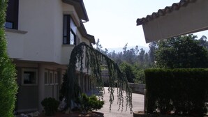 A two-story building with a covered driveway, a hanging vine, and a well-maintained hedge. - Motel Abalo (Catoira)