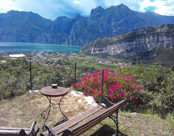 A bench and table overlooking a mountainous landscape with a lake and a village below. - B&B Garden Belvedere (Nago-Torbole)