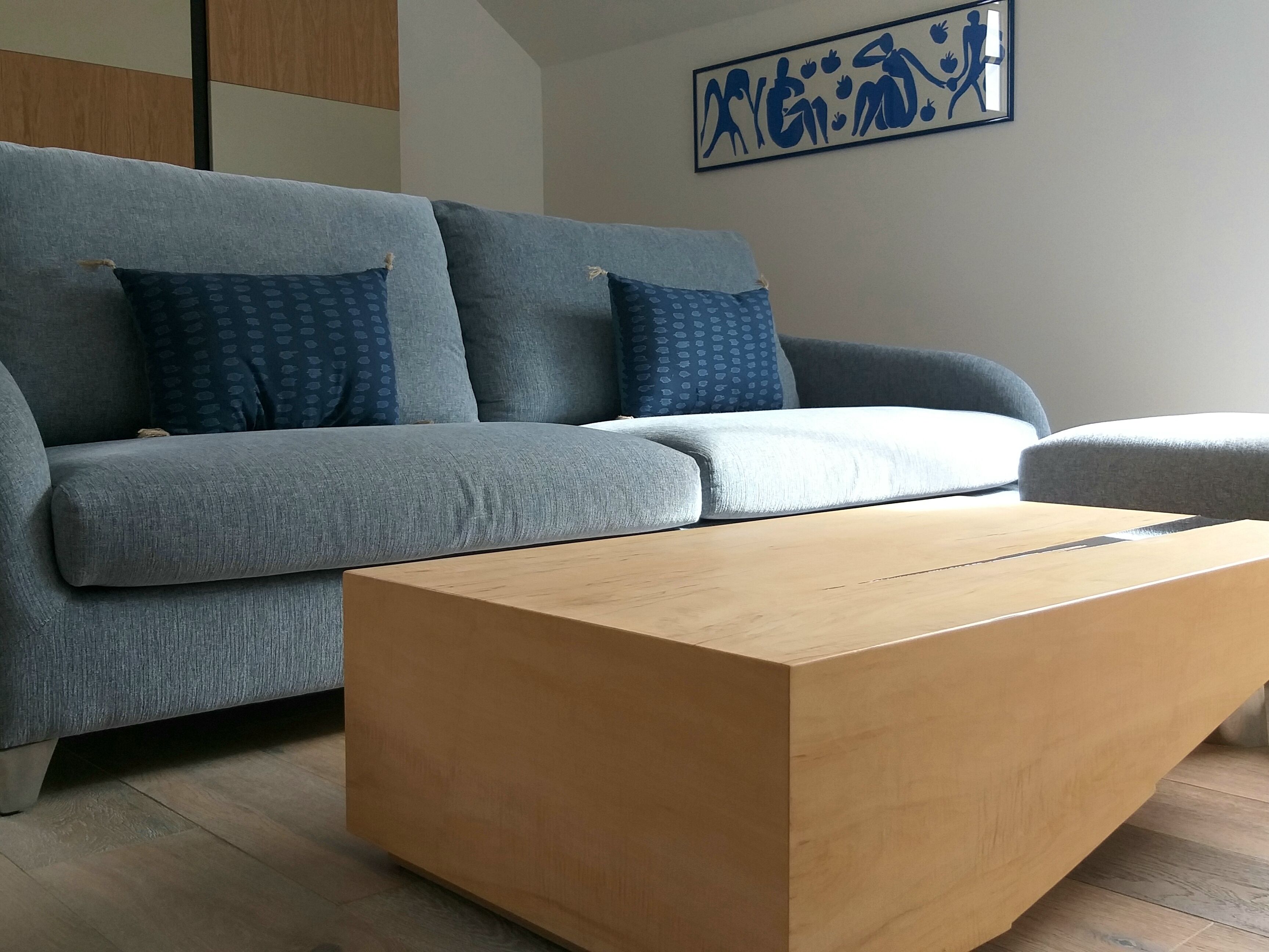 A modern living room with a grey sofa, blue patterned pillows, and a wooden coffee table.