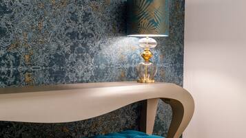 A modern room with a curved console table, a blue upholstered bench, and a wall-mounted lamp with a patterned shade.