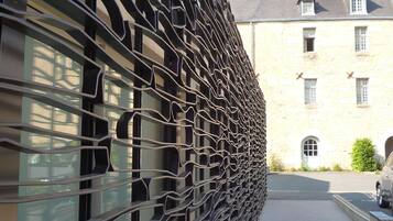 A building with a unique black metal facade and a stone building in the background.