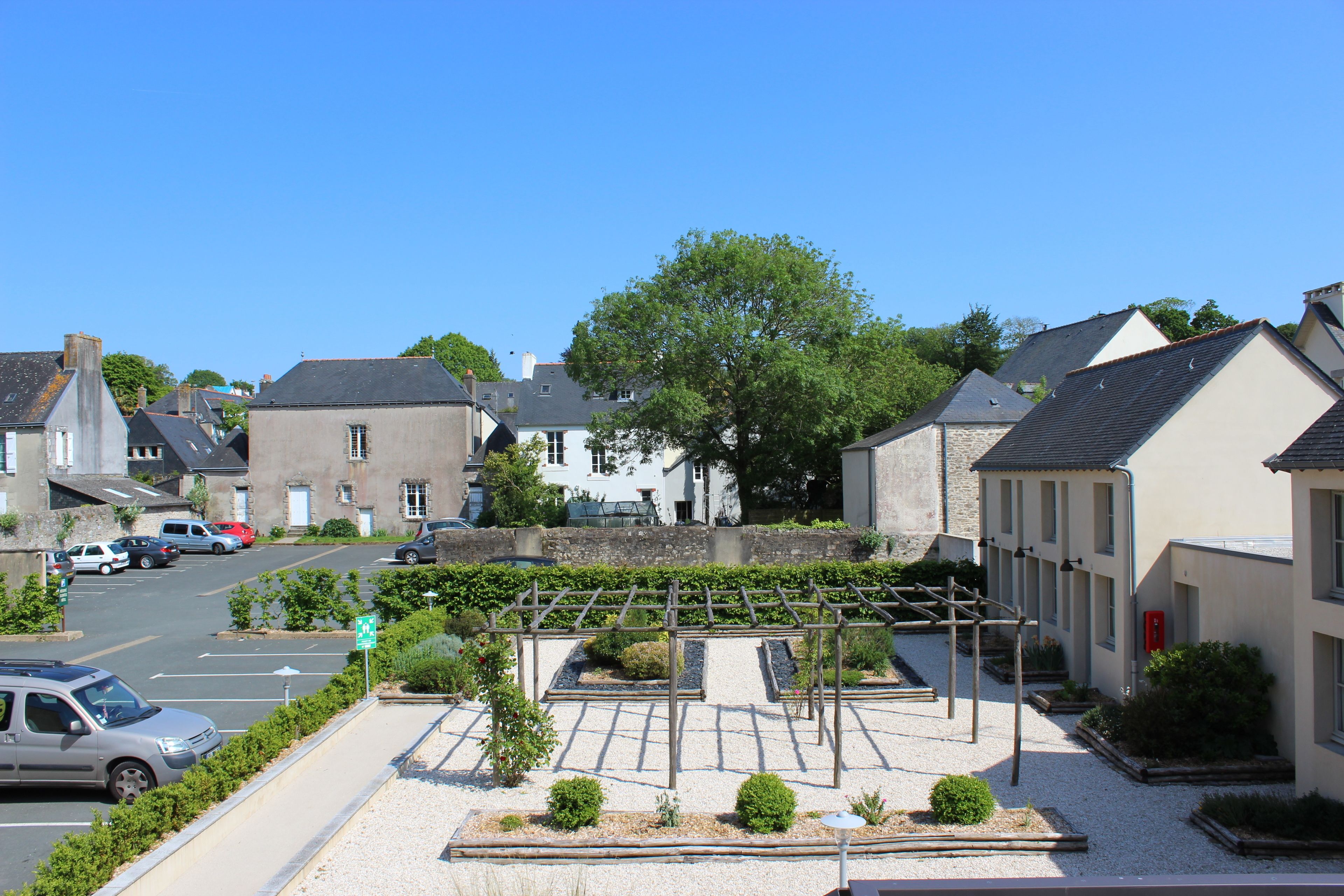 A residential area with houses, a parking lot, and a garden with a pergola.