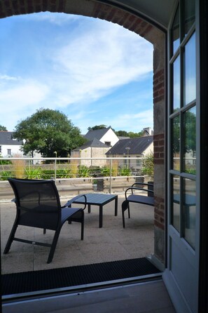 An outdoor patio area with a brick archway, two tables, and two chairs. - Hôtel Ginkgo (Quimper)