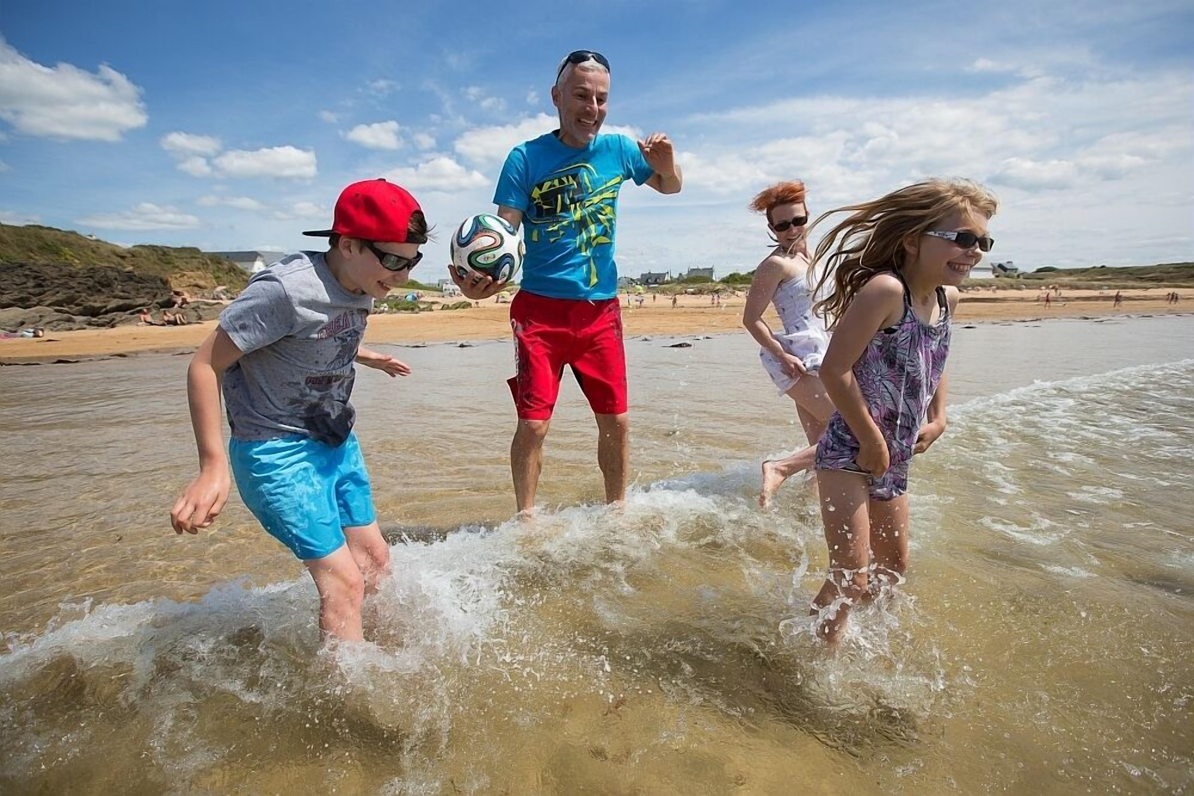 A beach scene with people playing in the water.