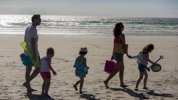 Une famille se promène sur une plage de sable, avec l’océan en arrière-plan.