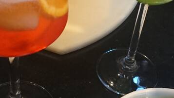 A kitchen counter with two glasses of beverages, one with a red drink and the other with a green drink, and a dirty white plate.