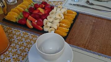 A breakfast setting with a fruit platter, white plates, and a cup of coffee.