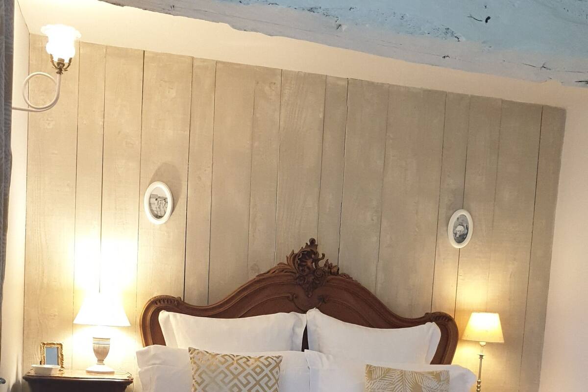 Et soveværelse med en træseng, to sengeborde med lamper og et trælofts.