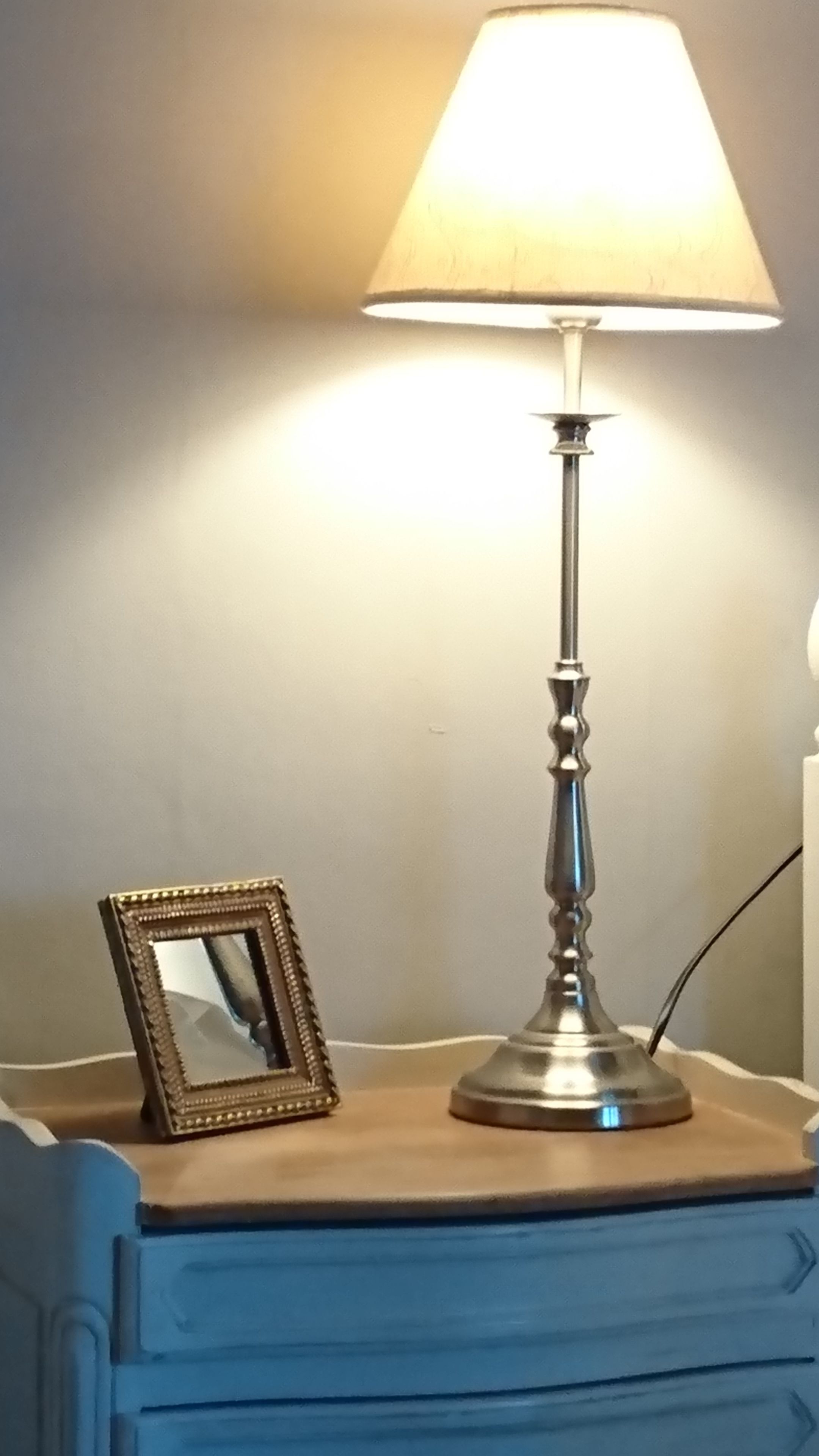 A bedside table with a lamp and a framed picture.