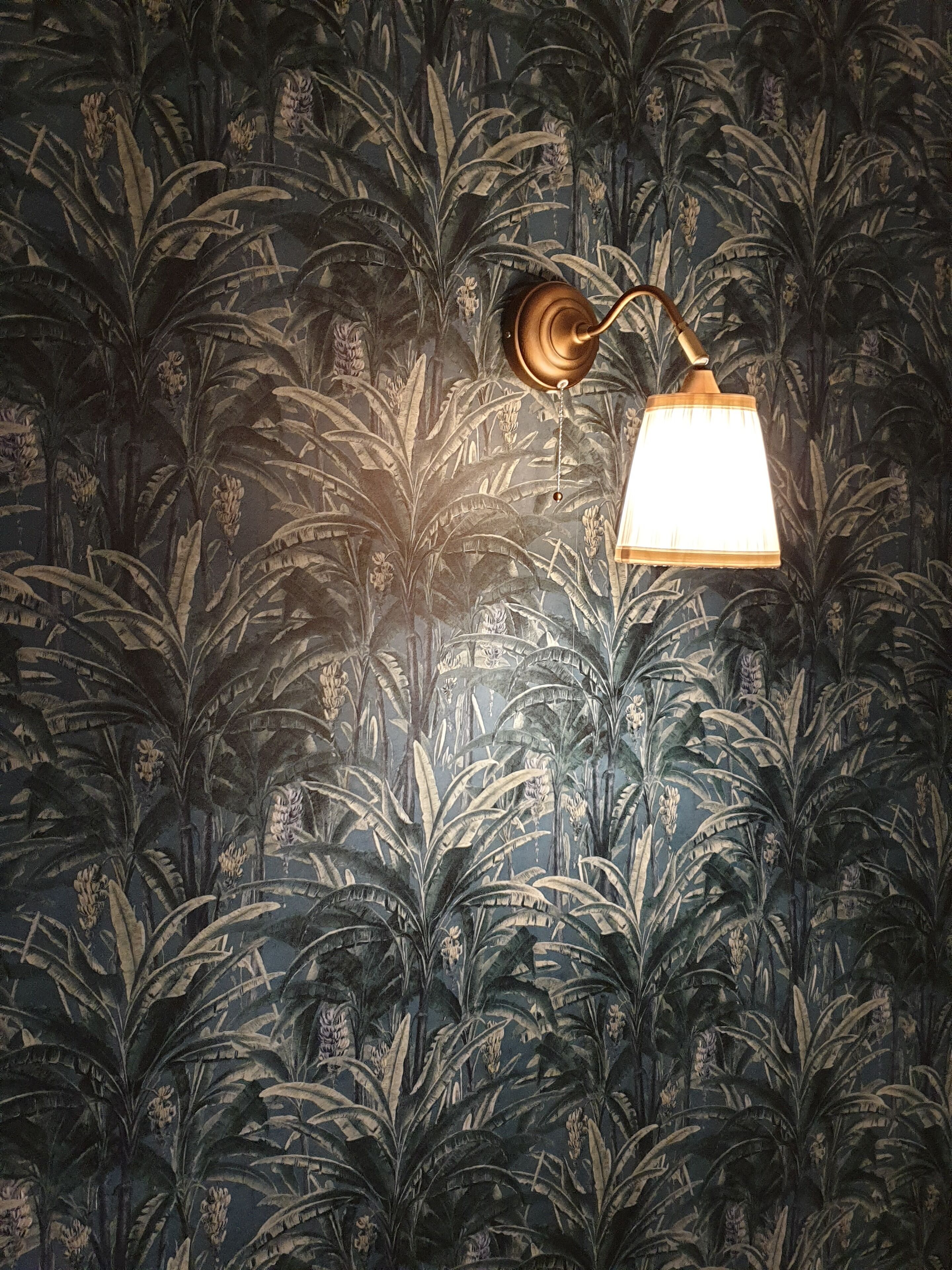 Un muro decorato con una carta da parati botanica, con foglie e fiori dalle grandi dimensioni.