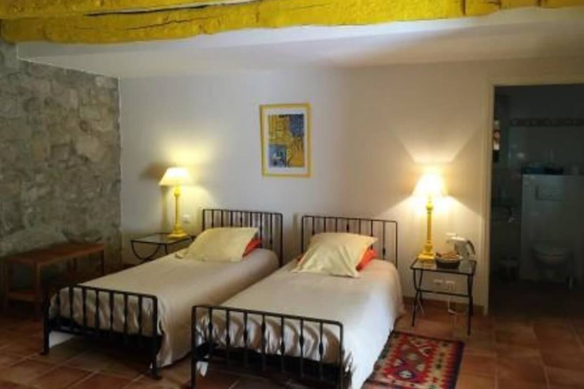 Ein Zimmer mit zwei Betten, einer Steinsäule, einem Gemälde und einem durch eine offene Tür einsehbaren Badezimmer.