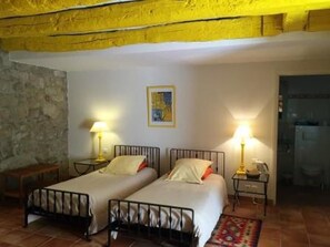 Ein Zimmer mit zwei Betten, einer Steinsäule, einem Gemälde und einem durch eine offene Tür einsehbaren Badezimmer.