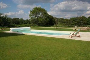Ein Schwimmbecken mit einer Liege in einer grünen Wiese.