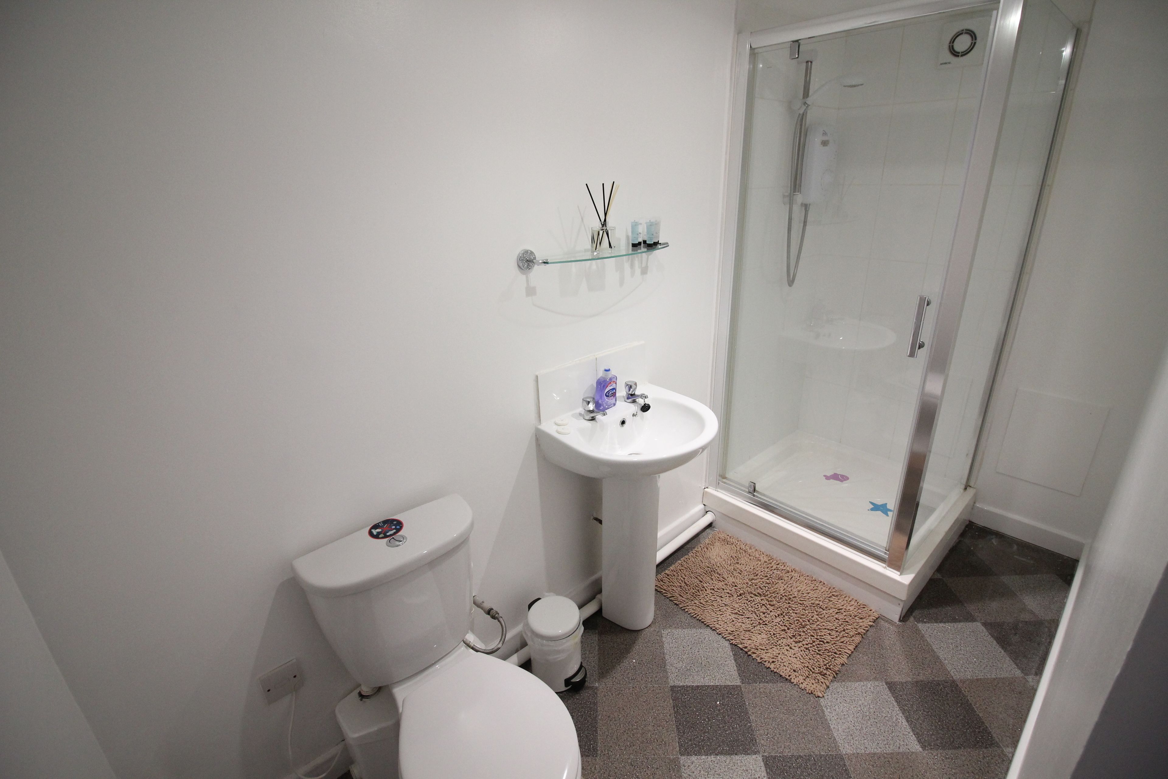 A bathroom with a toilet, sink, and glass-enclosed shower.