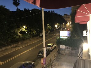 A nighttime street view with parked cars, a pedestrian crossing, and a building with a lit sign. - Etnea glamour house (Catania)