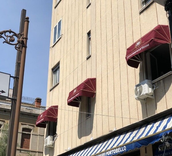 A building with multiple windows, some with awnings, and a sign for 'Portobello' at the bottom. - Etnea glamour house (Catania)