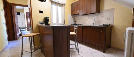 A kitchen with wooden cabinets, a countertop, a sink, and two bar stools.