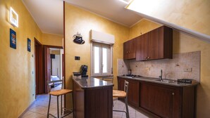 A kitchen with wooden cabinets, a bar counter, and a window. - Vico Tauro House (Taormina)
