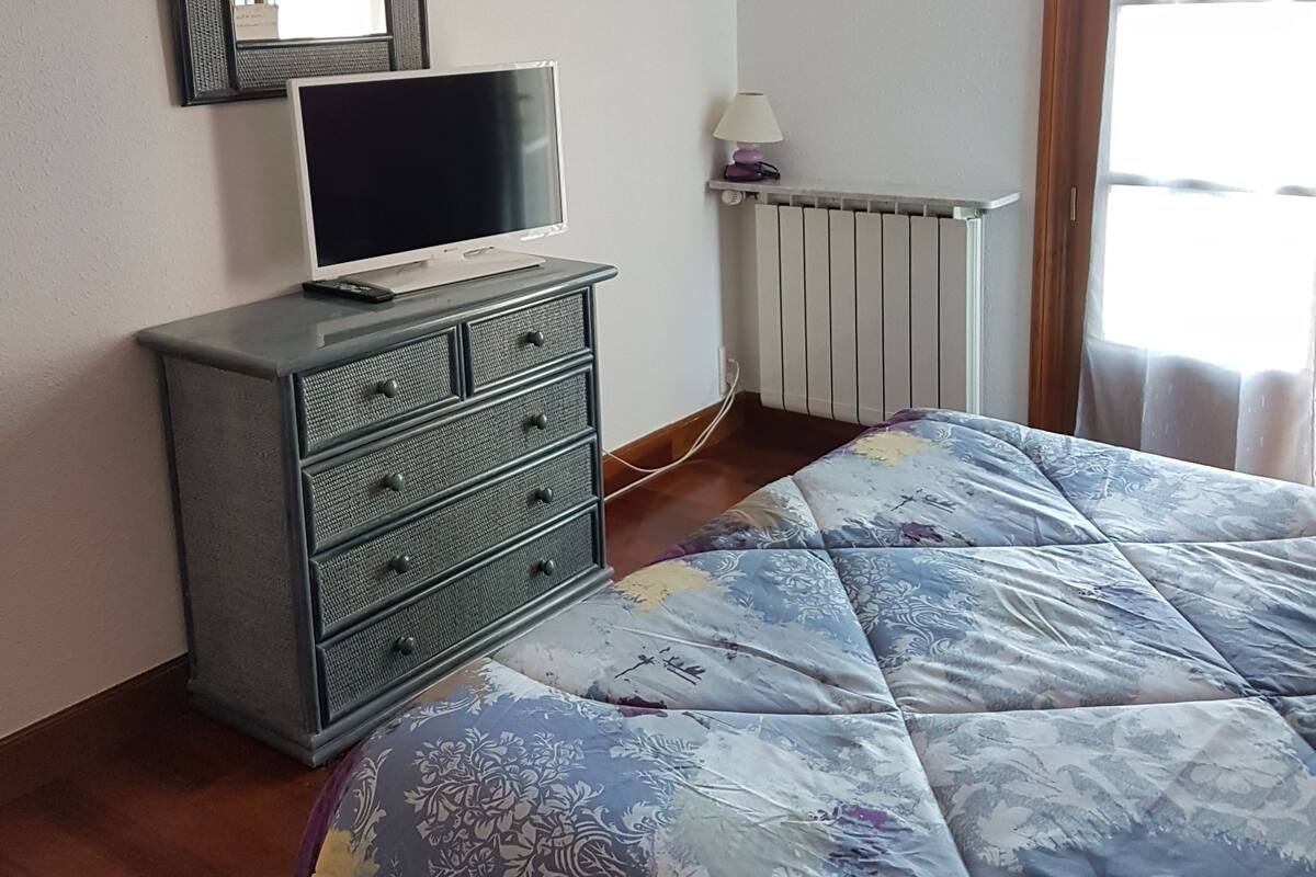 Makuuhuoneessa on sänky, lipasto, televisio ja patteri.