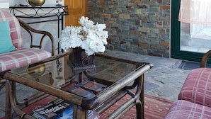 Una sala acogedora con un sofá de madera, una mesa de centro de cristal y una pared de piedra.