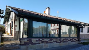 Una casa con techo de tejas, ventanas grandes y fachada de piedra.