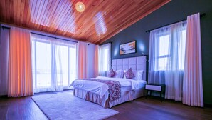 Une chambre spacieuse avec un grand lit, une table de chevet et une fenêtre avec des rideaux.