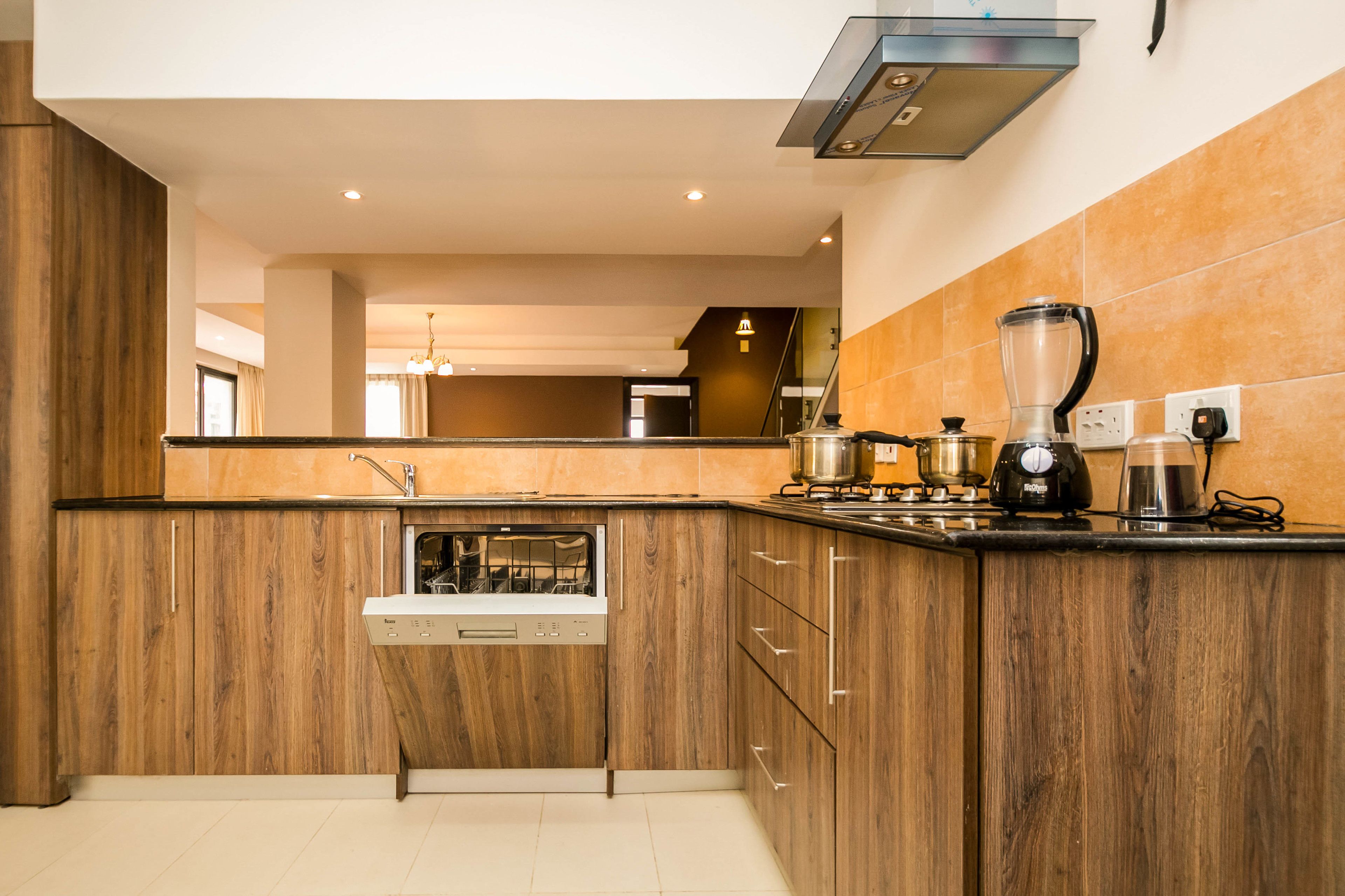 Una cocina moderna con armarios de madera, lavavajillas integrado y cafetera.
