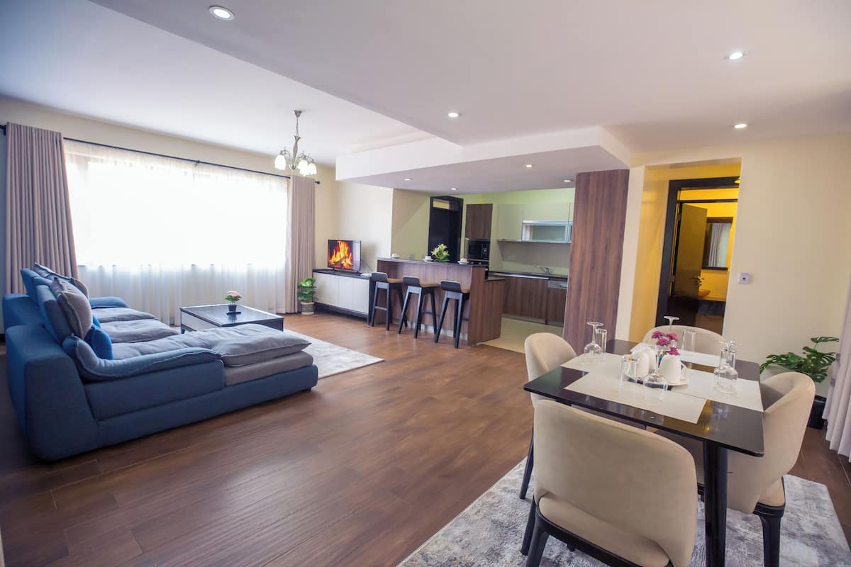 A modern living room with a sofa, dining table, and kitchen in the background.