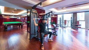 Een sportschool met houten vloeren, trainingsapparatuur en een pooltafel.