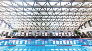 En indendørs swimmingpool med et glastag og metalbjælker.