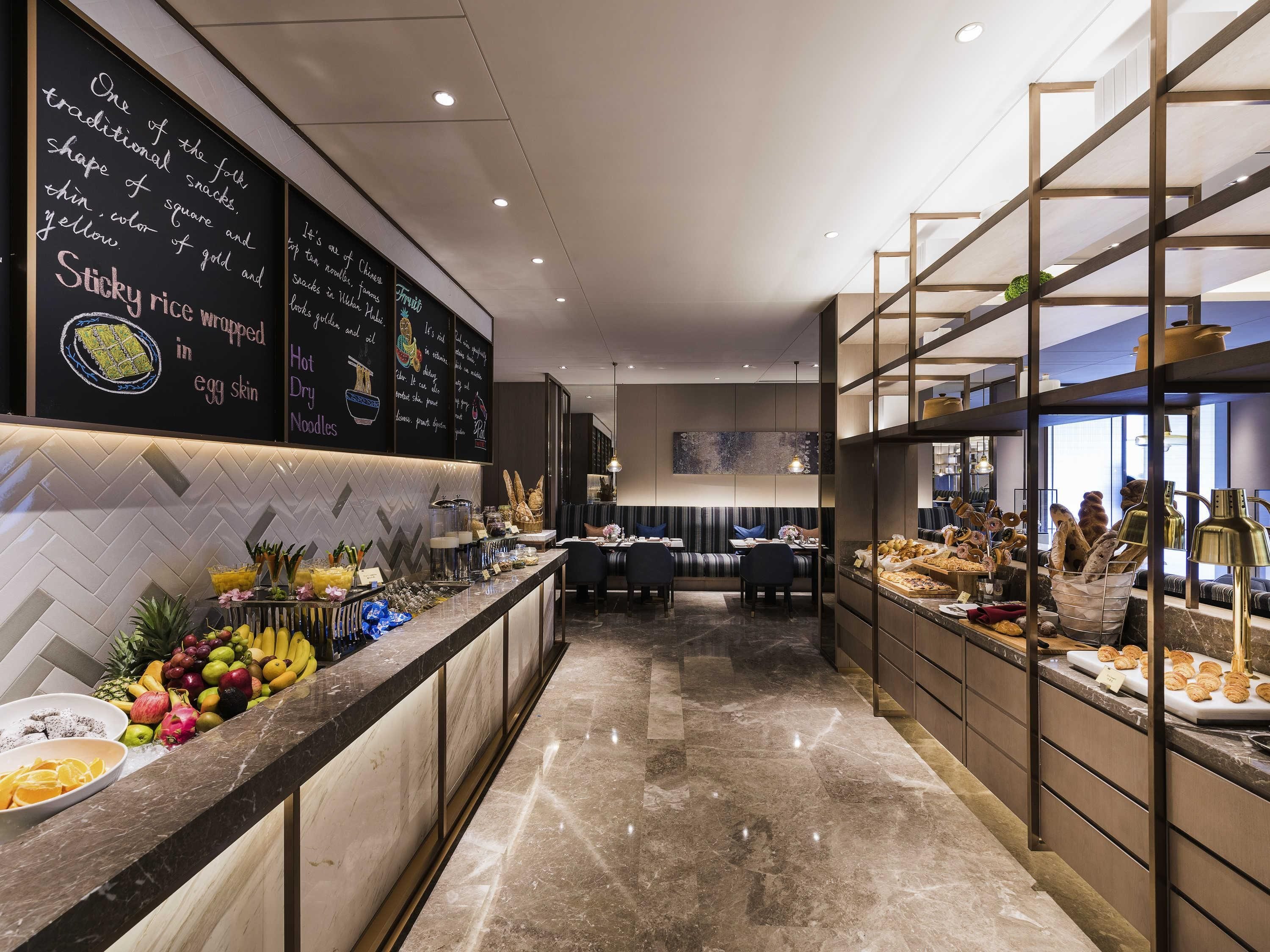 A hotel lobby with a marble floor, a reception desk, and a buffet area with various food items.