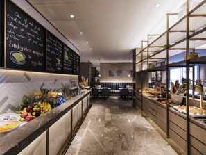 Un hall d’hôtel doté d’un sol en marbre, d’un comptoir de réception et d’un espace buffet proposant divers plats.