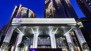 Un hôtel moderne doté d’une entrée imposante, de grandes fenêtres en verre et d’une façade bien éclairée.