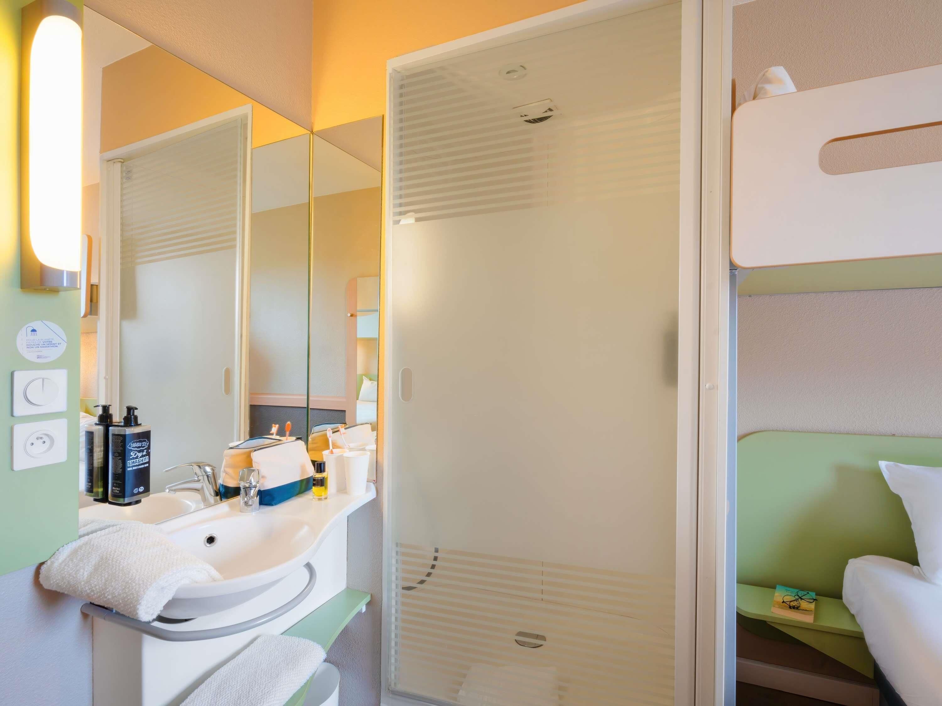 Baño con lavabo, espejo, toalla y zona de ducha.