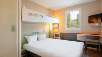 Une chambre avec un lit superposé, un bureau avec une chaise, une télévision et une fenêtre donnant sur des arbres.