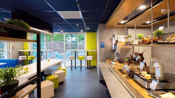 Un café moderno con asientos, una barra con productos alimenticios y vistas al exterior.
