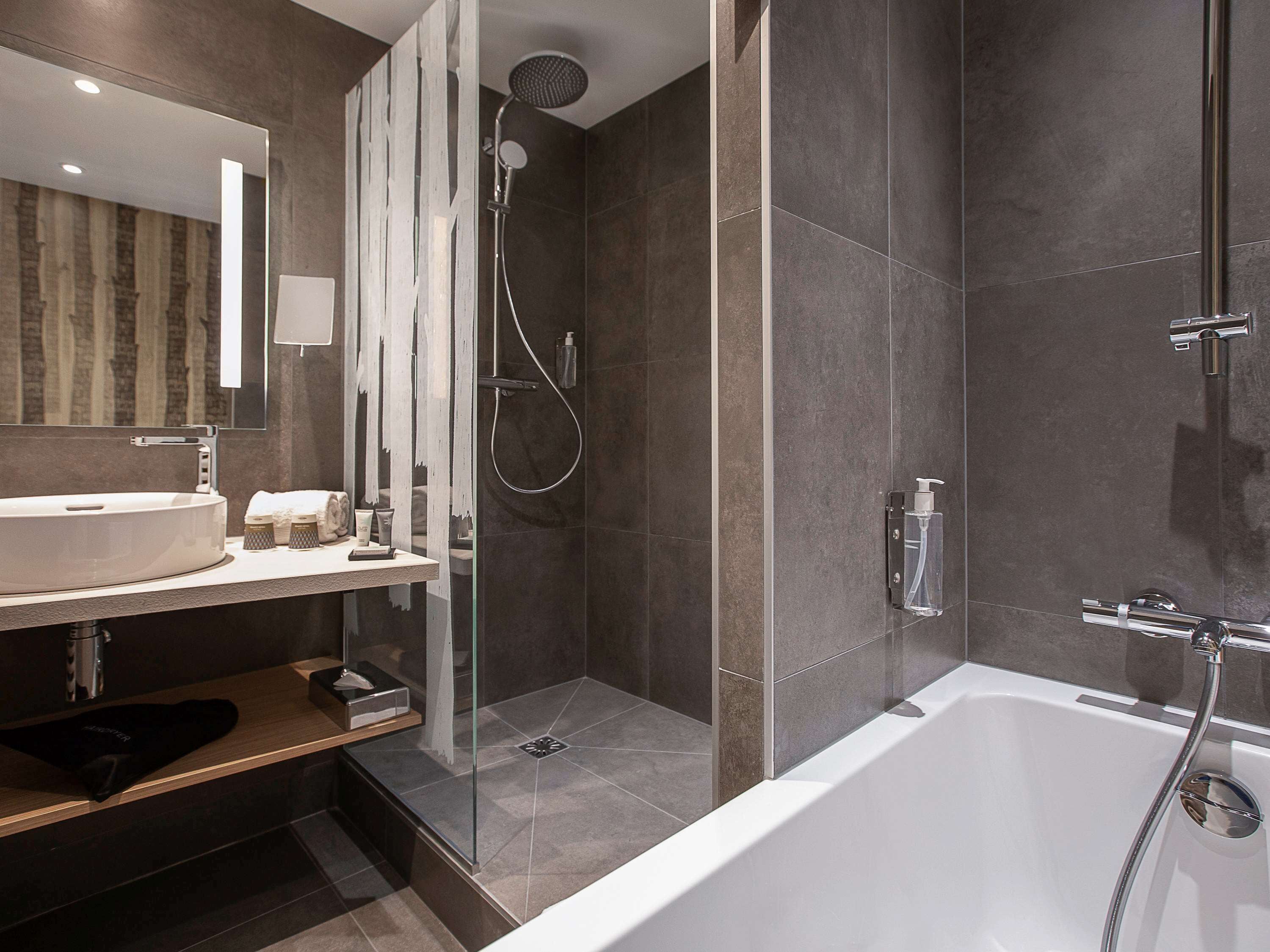 Un baño moderno con bañera, ducha y tocador con lavamanos.