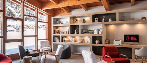 A modern interior with wooden beams, a bookshelf, and several rocking chairs.