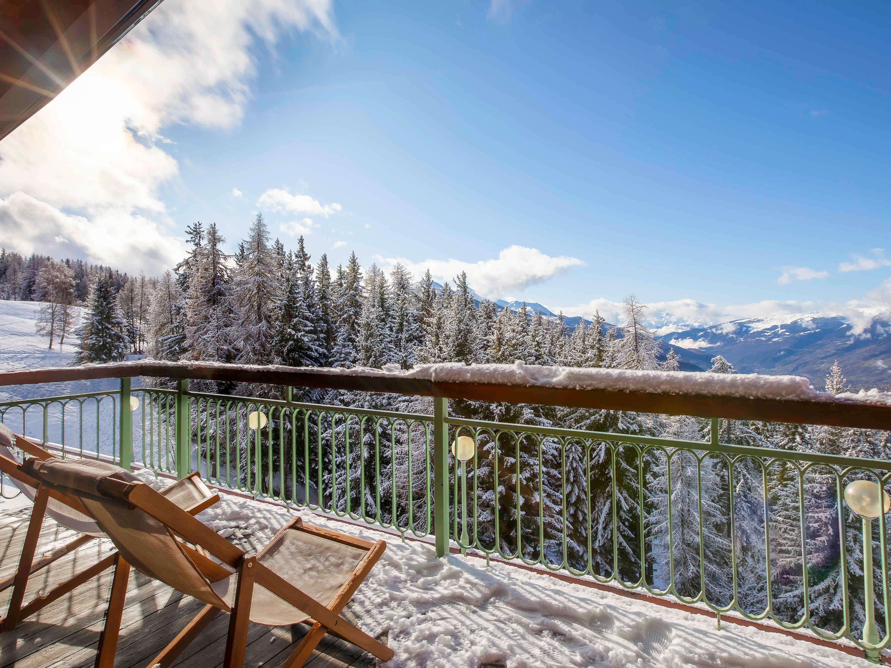 Varanda com vista para árvores e montanhas cobertas de neve.